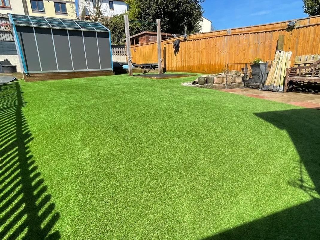 Artificial grass garden with patio view and planting borders