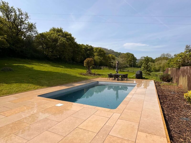 Beige pool slabs installed around outdoor swimming pool