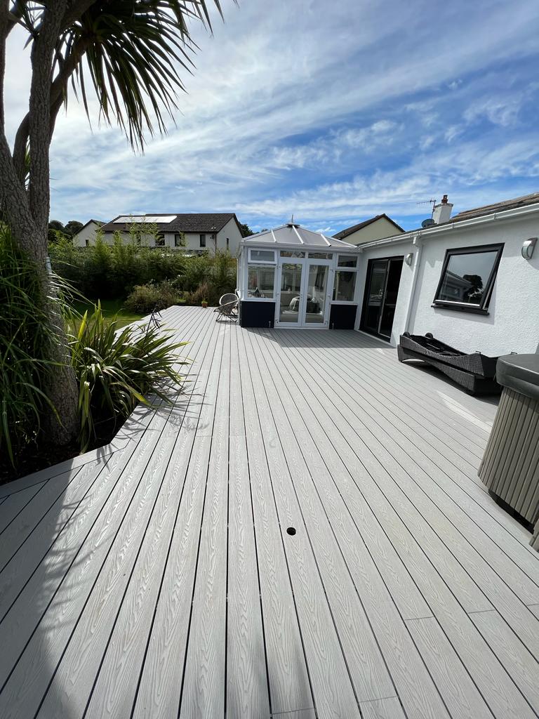 Grey composite decking with palm trees in garden