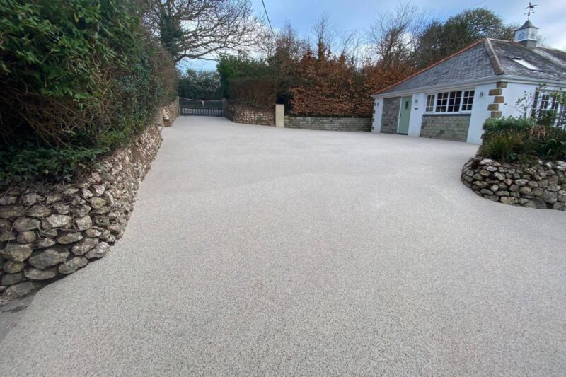 Cream resin bound driveway with stone wall borders leading to cottage