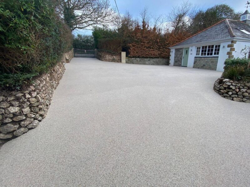 Cream resin bound driveway with stone wall borders leading to cottage