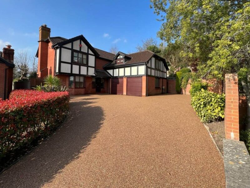 Golden resin bound driveway outside Tudor-style house with landscaped garden