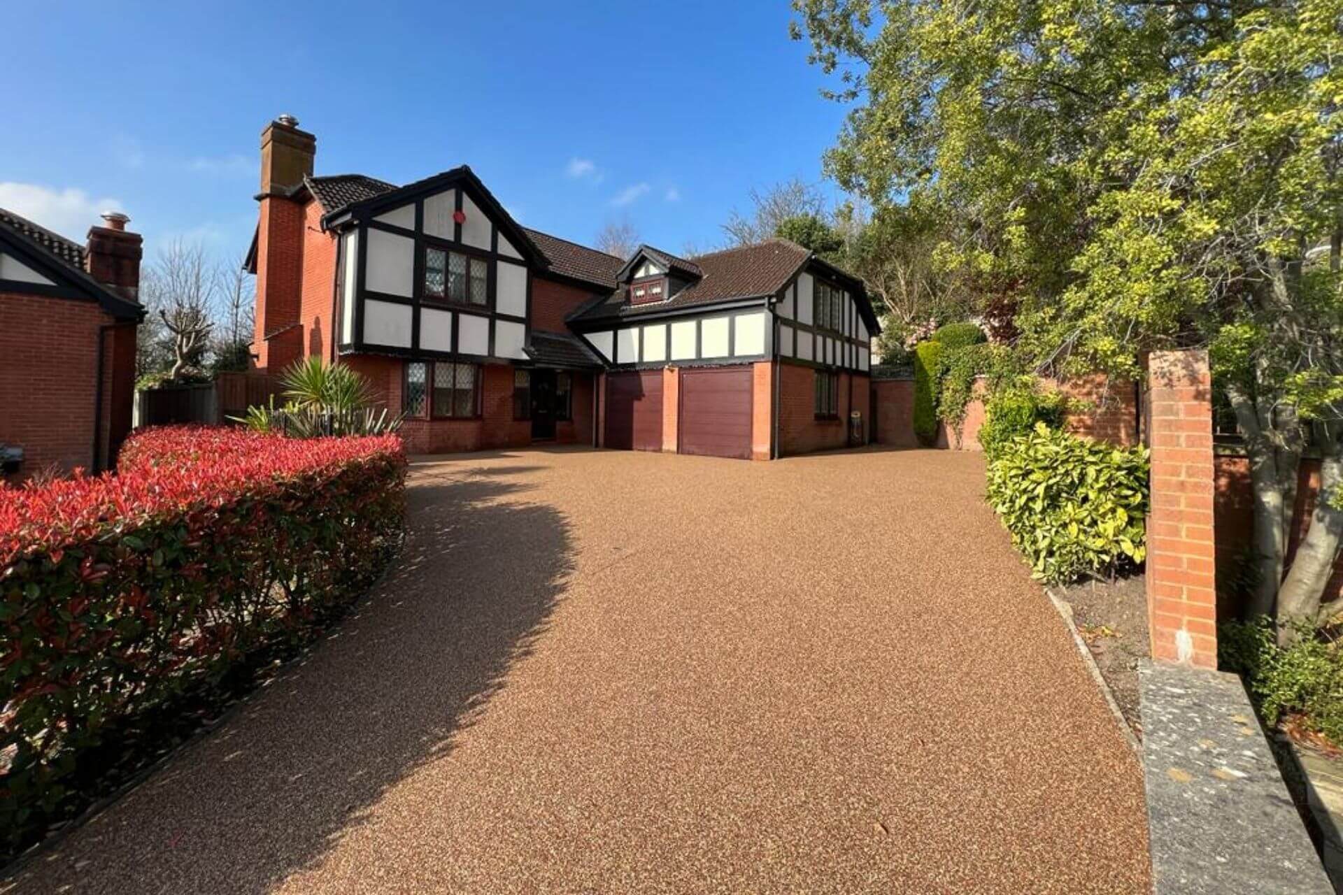 Golden resin bound driveway outside Tudor-style house with landscaped garden