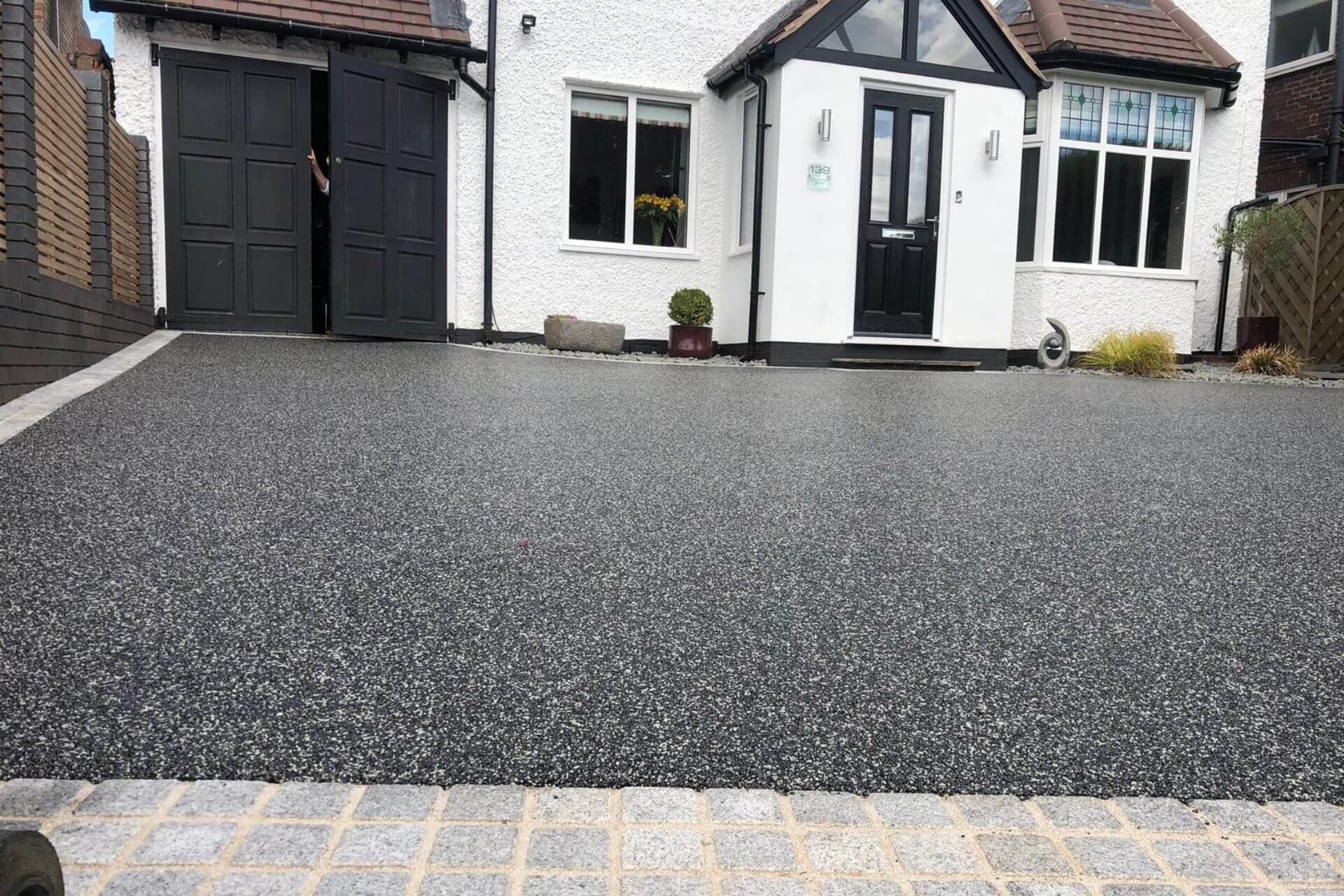 Grey resin bound driveway with granite block edging outside white house
