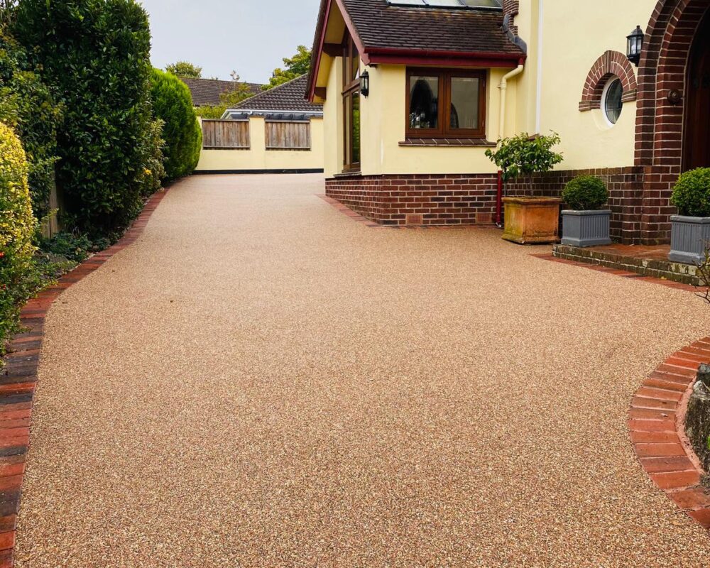 Long resin bound driveway with block paved edging in mature garden, Newton Abbot