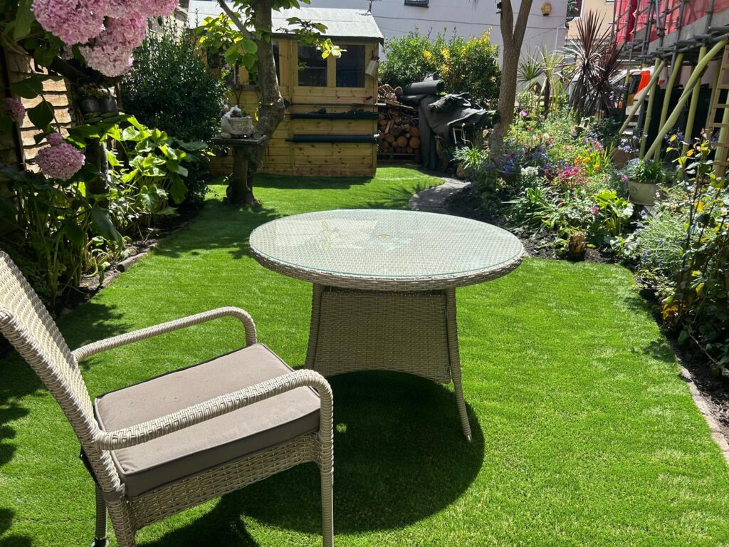 Rattan seating on new artificial grass with established garden borders, Teignmouth