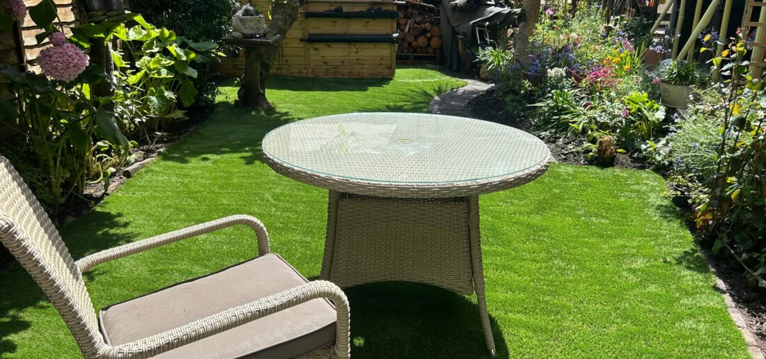 Rattan seating on new artificial grass with established garden borders, Teignmouth
