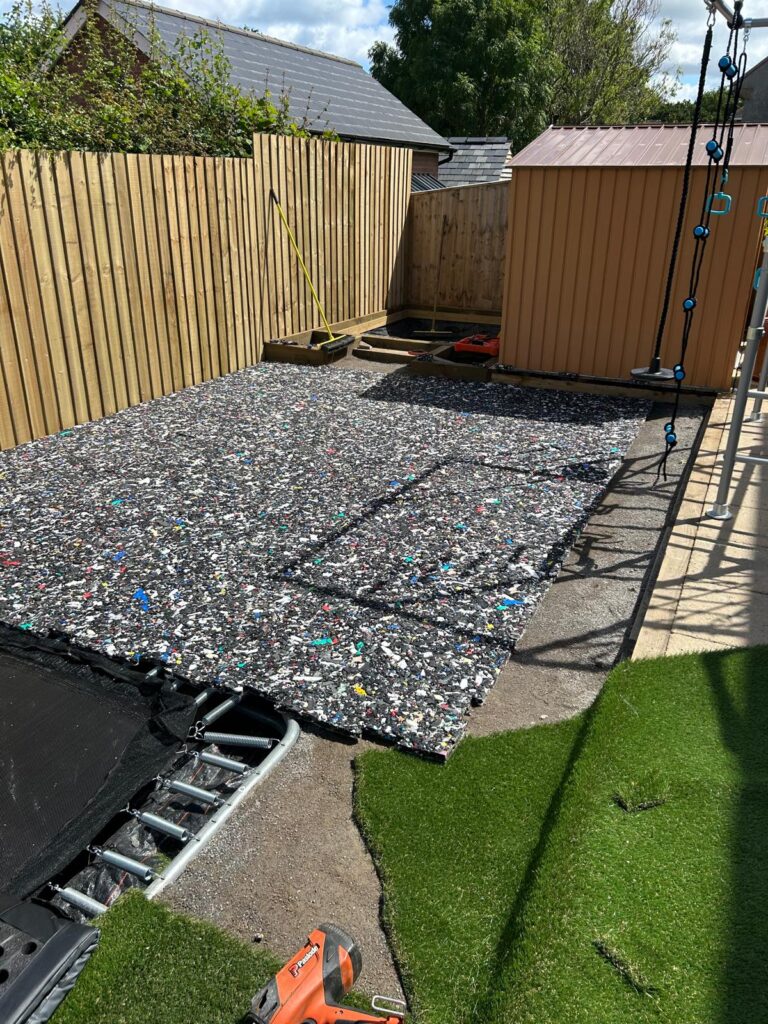 Decorative aggregate bed edged with timber sleepers beside artificial grass in a sensory garden