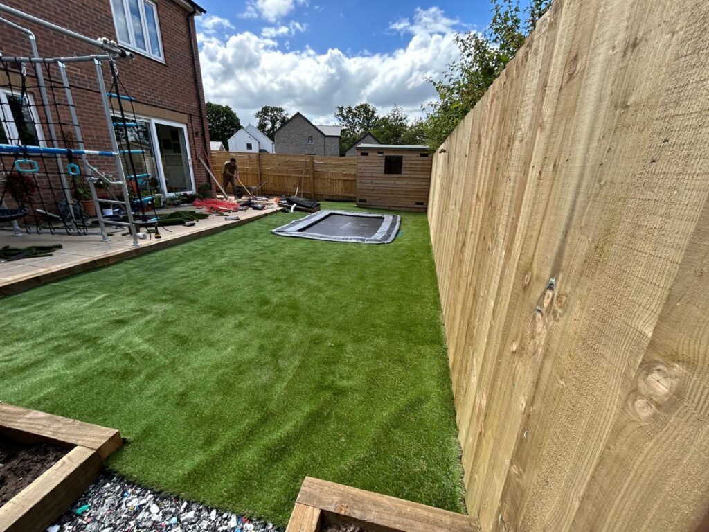 Finished sensory garden with artificial grass, in ground trampoline and close board fencing
