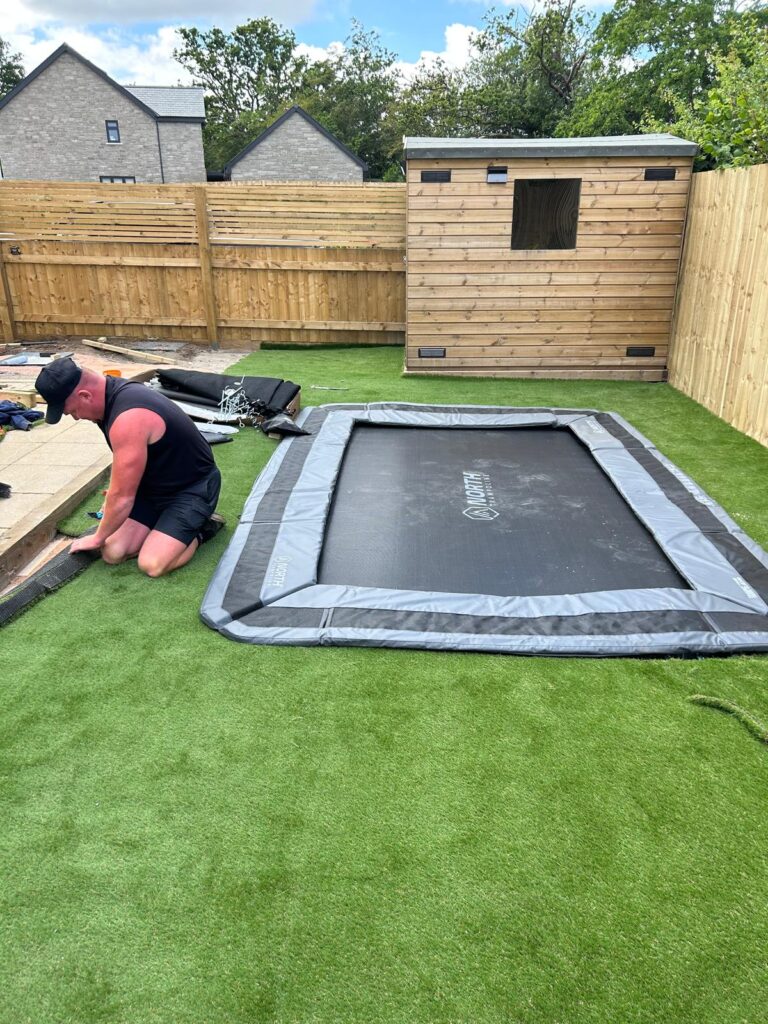 In ground trampoline being set flush into artificial grass in a sensory garden